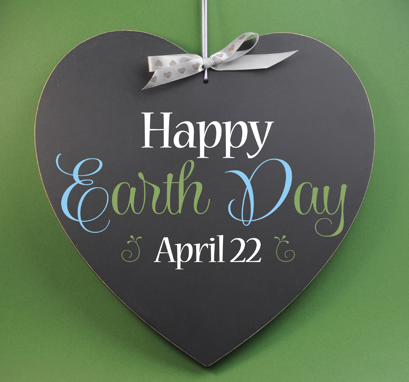 Happy Earth Day April 22, message sign greeting on a heart shaped blackboard against a green background.